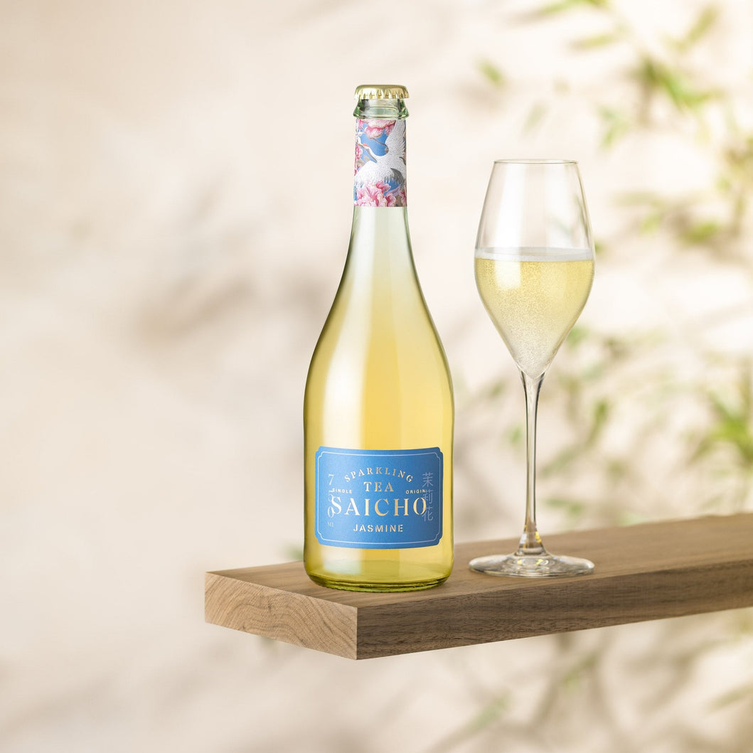 Bottle of Saicho Sparkling Jasmine Tea with a glass on a wooden shelf against a blurred natural background